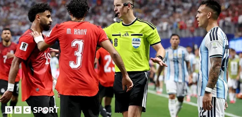 Joueurs et arbitre discutant sur le terrain de football