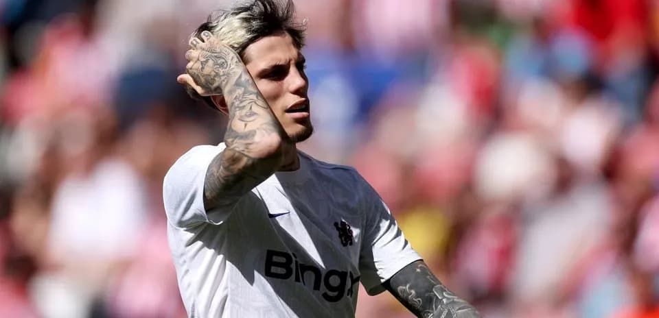 Joueur en maillot blanc touchant ses cheveux sur le terrain