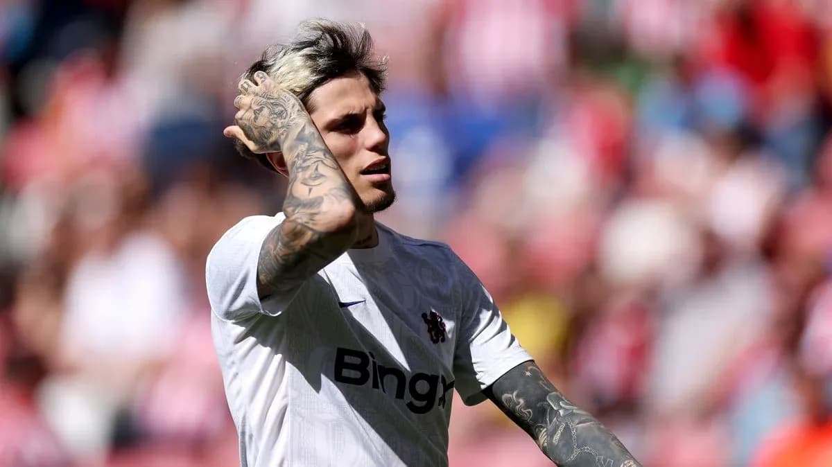 Joueur en maillot blanc touchant ses cheveux sur le terrain