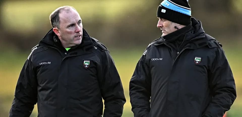 Deux entraîneurs discutant sur le terrain d'entraînement