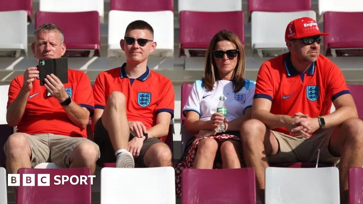 Supporters wearing England shirts sitting in stadium