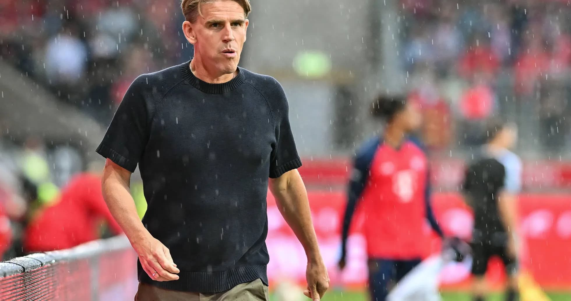 Entraîneur marchant sous la pluie sur le terrain