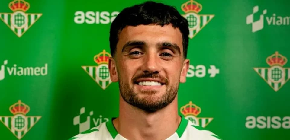 Joueur souriant devant un panneau du Real Betis