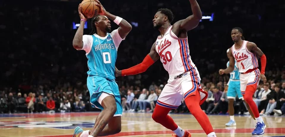 Joueur des Hornets dribblant sous pression des Nets