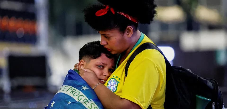 Supporters embracing, wrapped in Brazilian flag