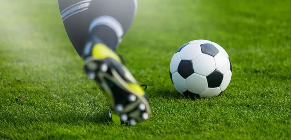 Joueur frappant un ballon de football sur gazon