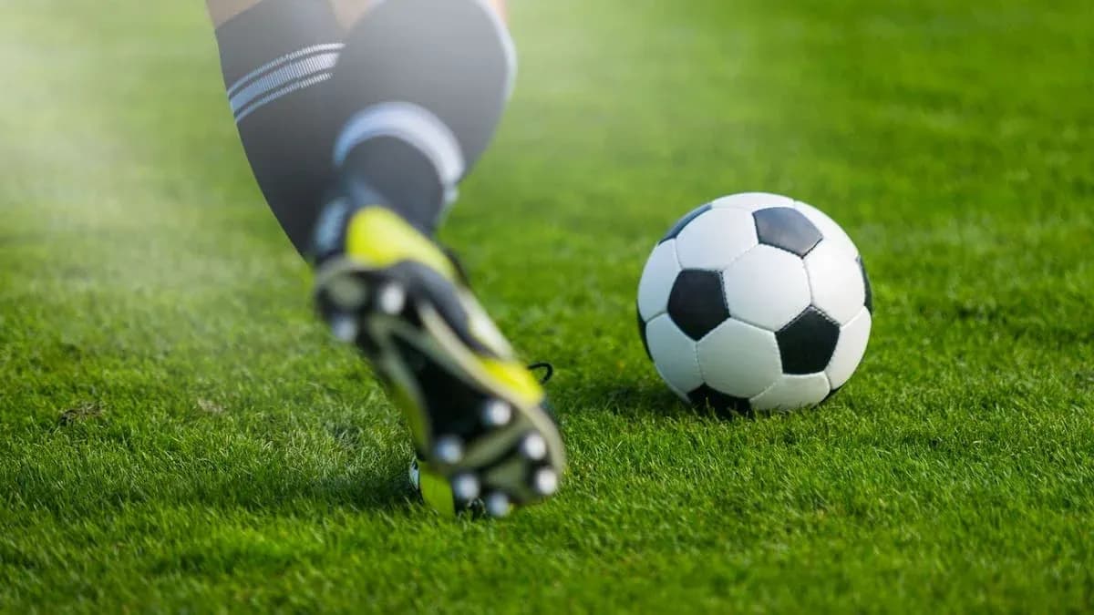 Joueur frappant un ballon de football sur gazon