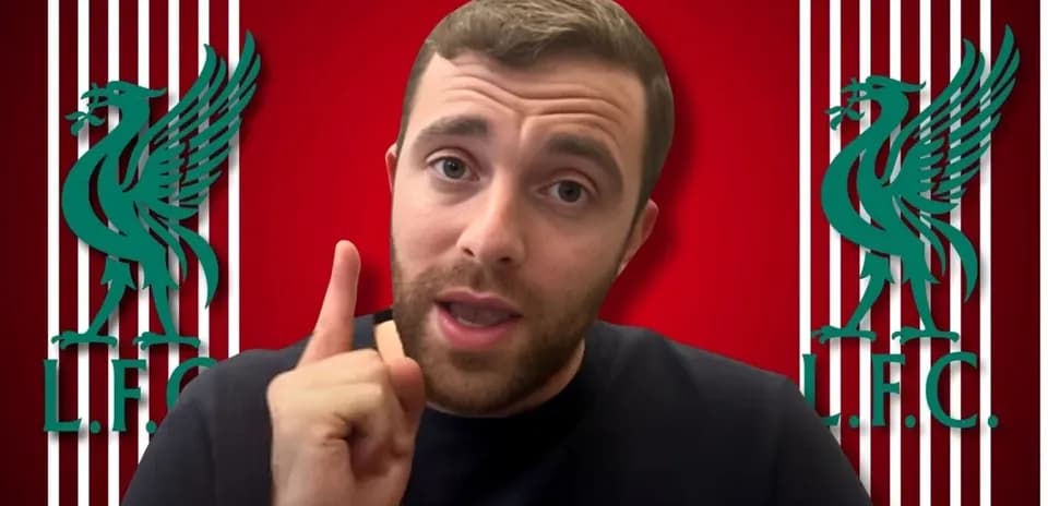 Person speaking in front of Liverpool FC logo