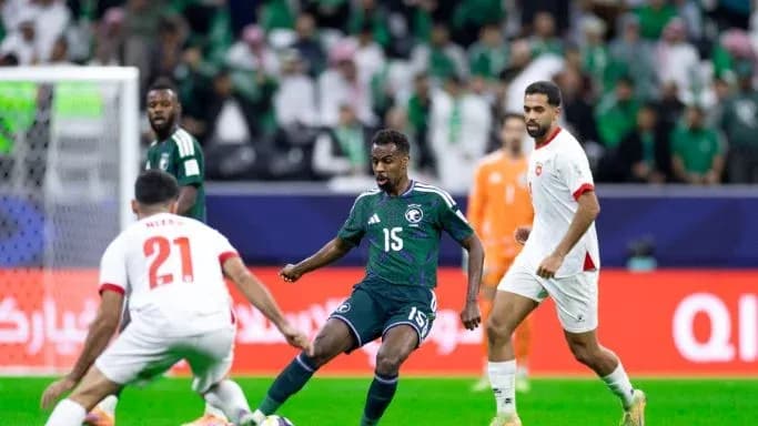 Joueur saoudien dribblant face à deux adversaires