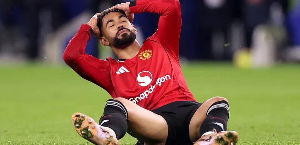 Joueur de Manchester United assis, se tenant la tête