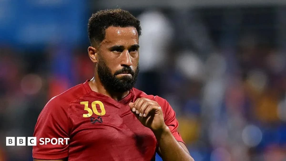 Joueur en maillot rouge, regard sérieux sur le terrain