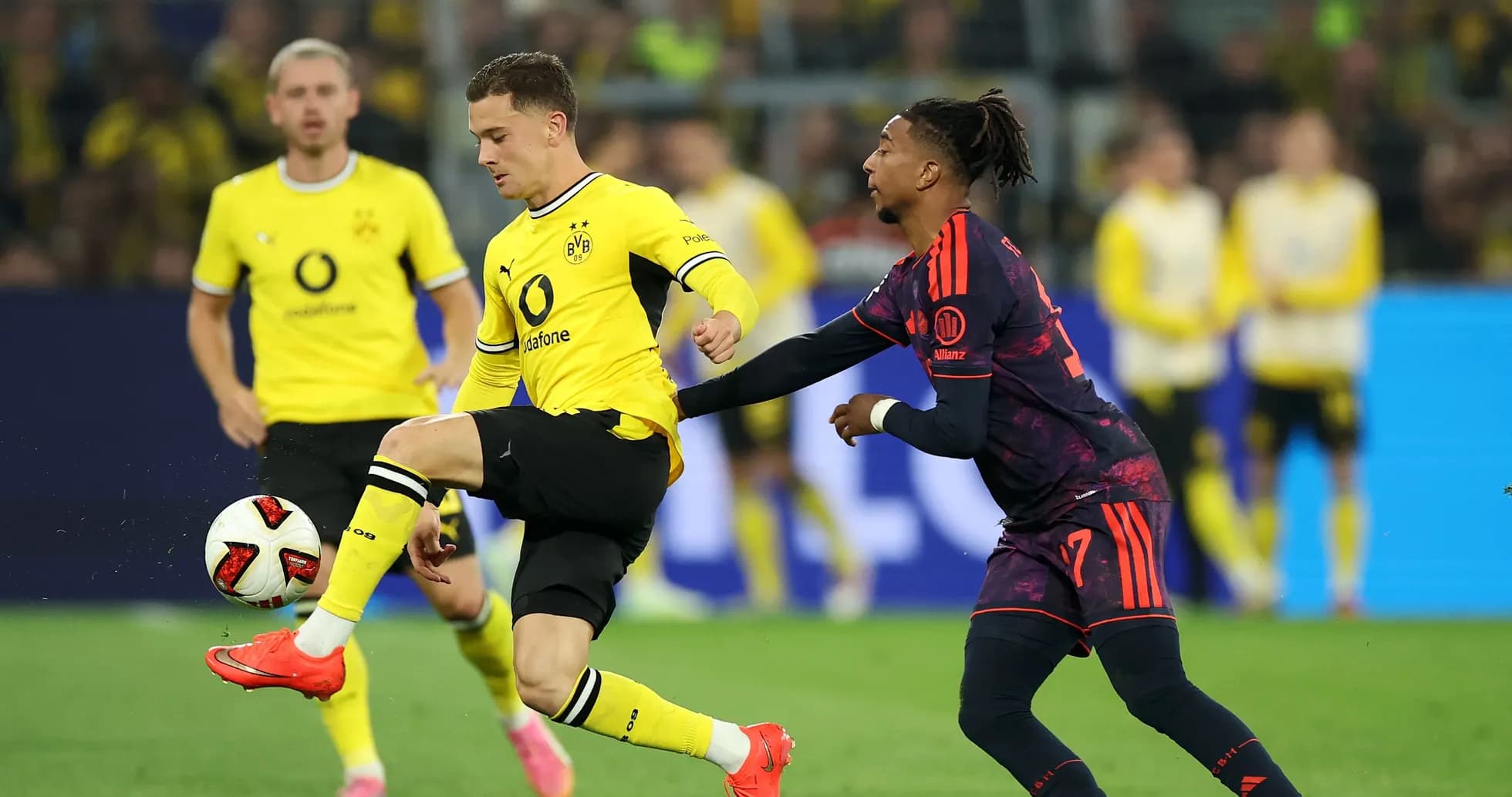 Joueur de Dortmund dribblant avec un adversaire en arrière-plan