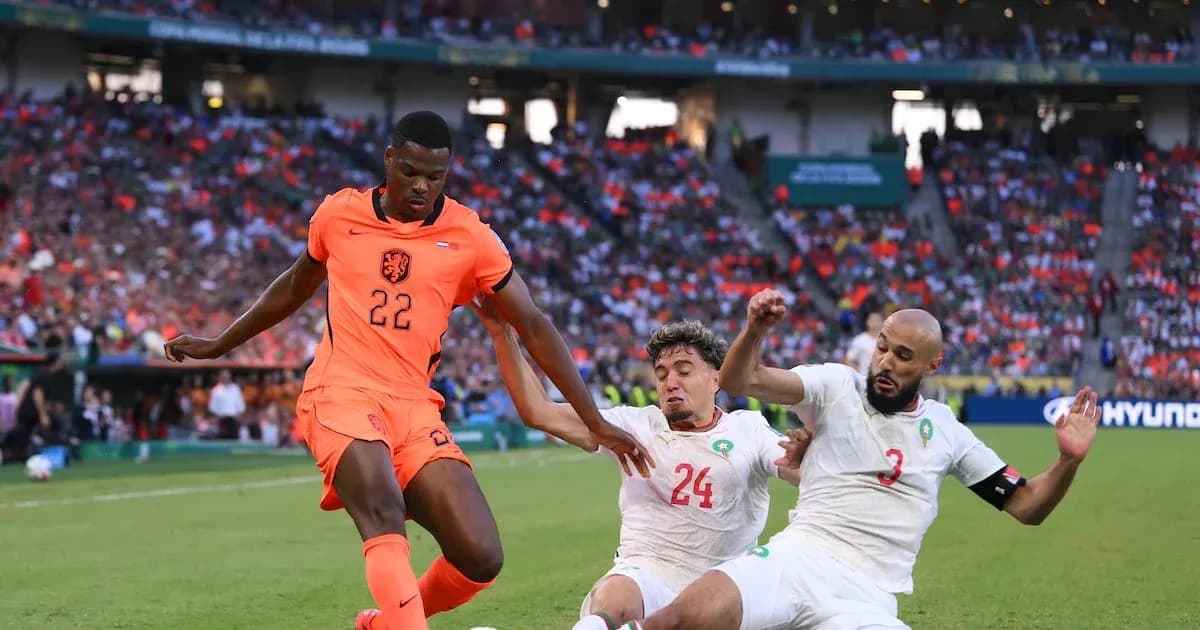 Joueur néerlandais dribblant entre deux défenseurs marocains