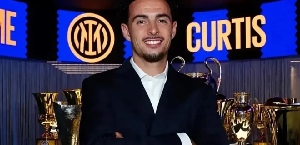 Homme souriant devant des trophées de football