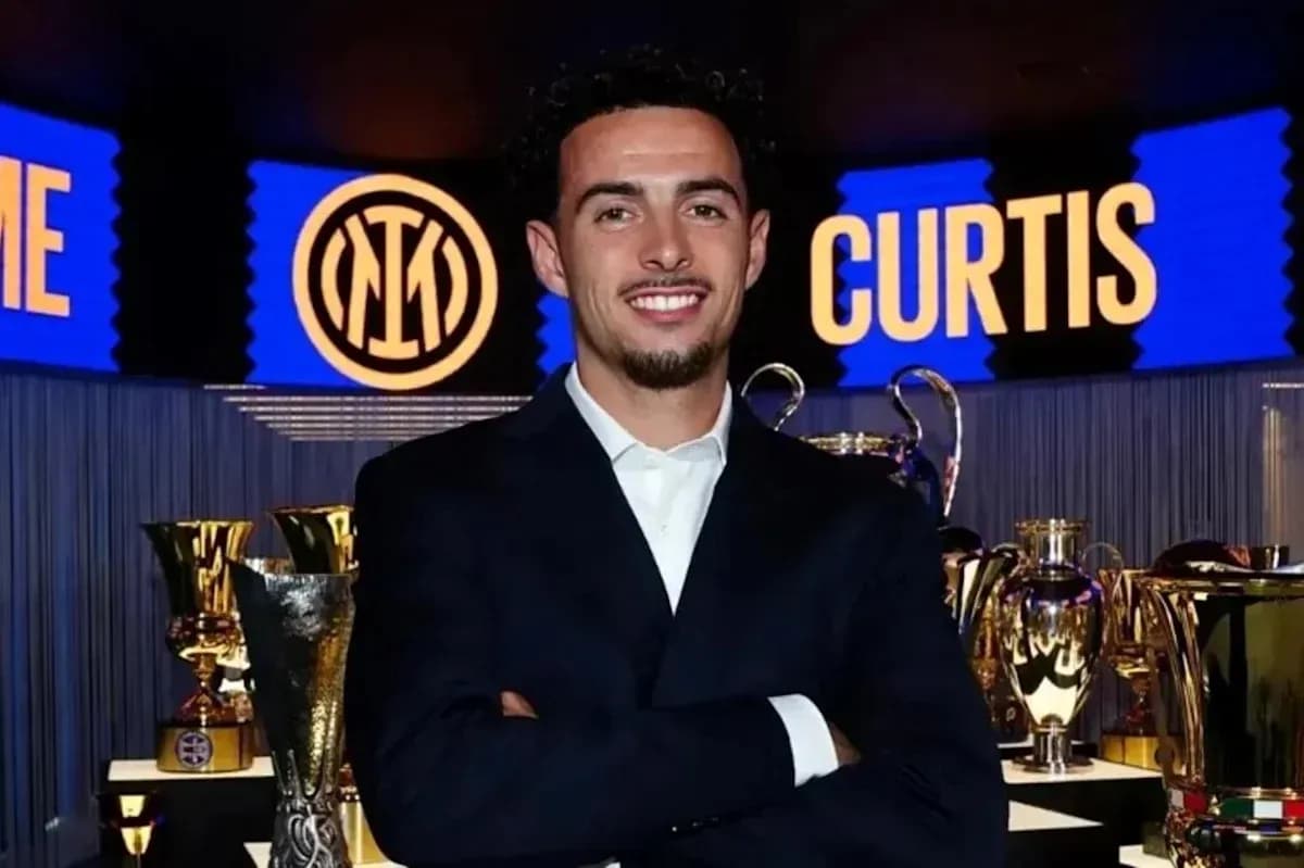 Homme souriant devant des trophées de football