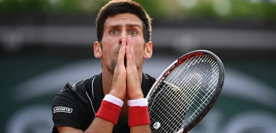 Joueur de tennis tenant sa raquette avec les mains jointes