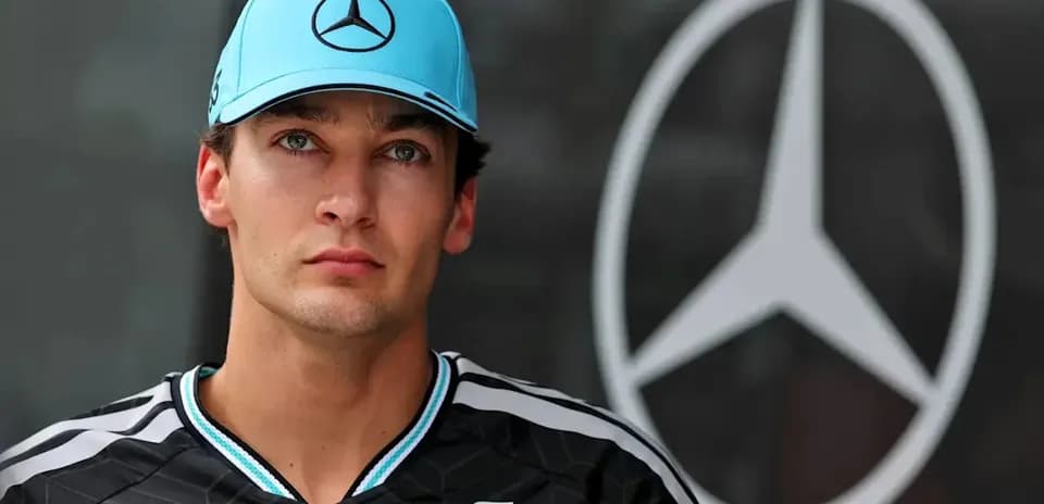 Pilote en tenue Mercedes devant le logo de l'équipe