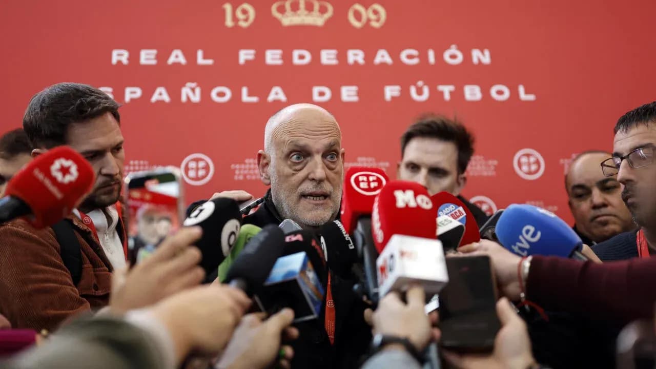 Person speaking at press conference surrounded by journalists