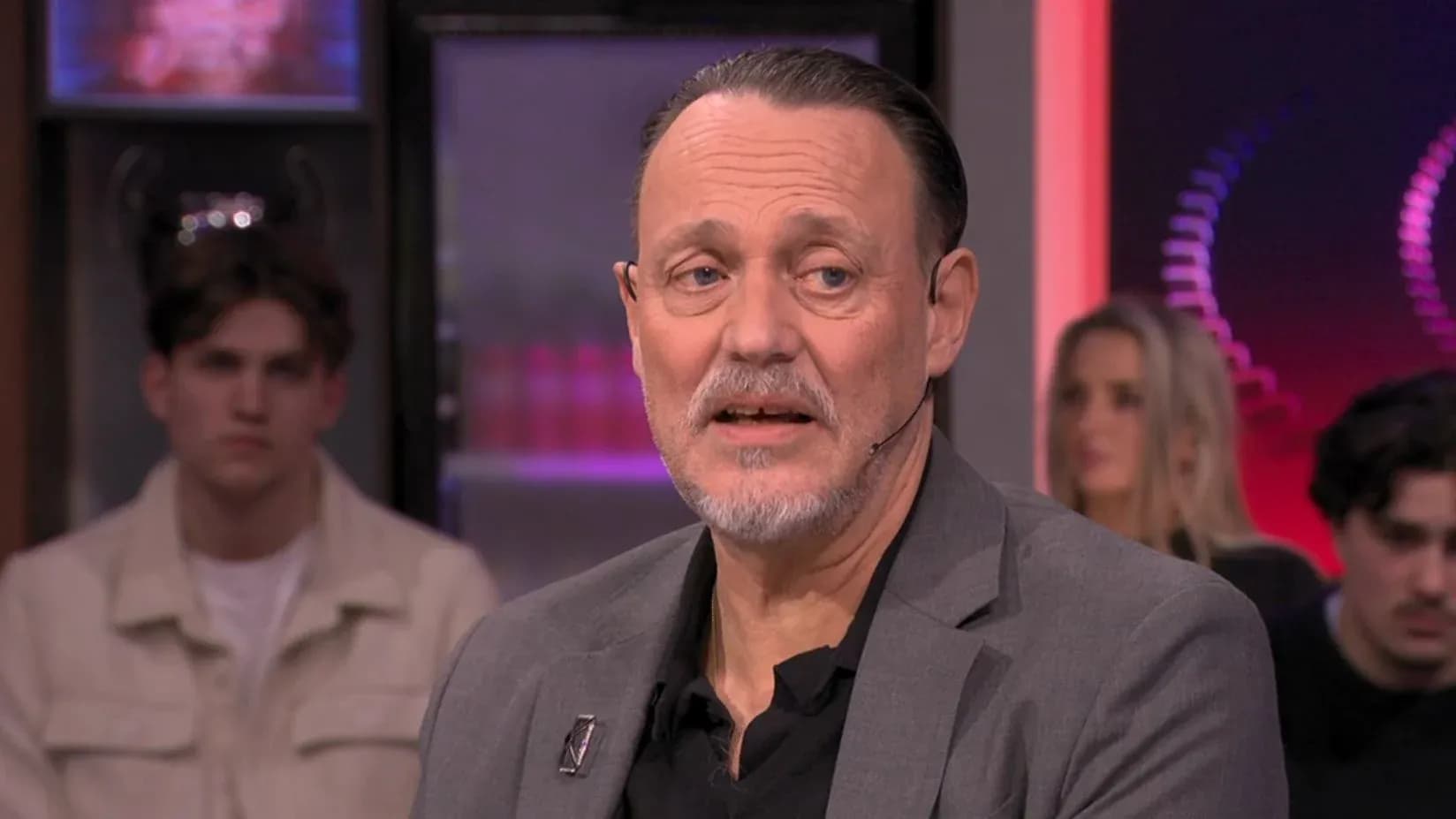 Homme parlant lors d'une émission avec public en arrière-plan