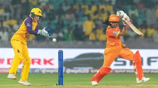 Batter playing a shot while wicketkeeper prepares
