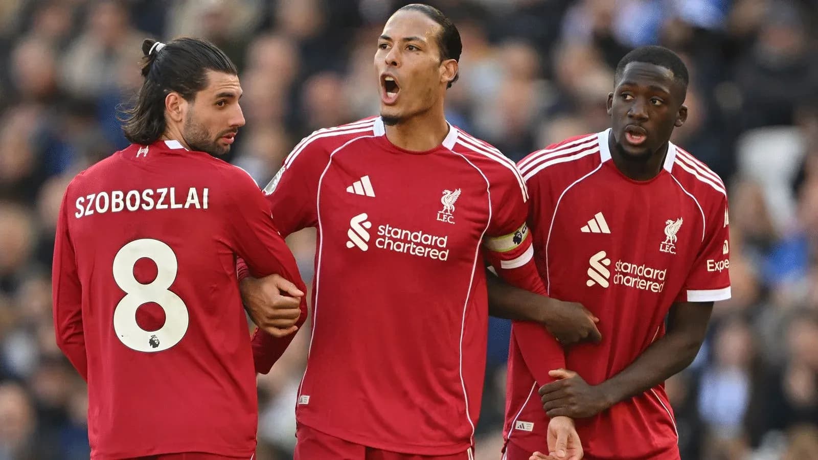 Trois joueurs de Liverpool discutant sur le terrain