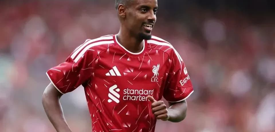 Joueur de Liverpool en maillot rouge souriant sur le terrain