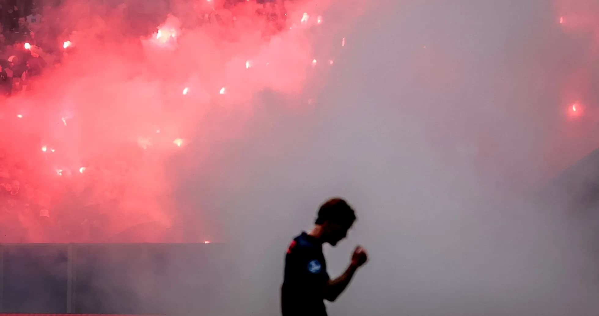Joueur célébrant avec fumigènes en arrière-plan