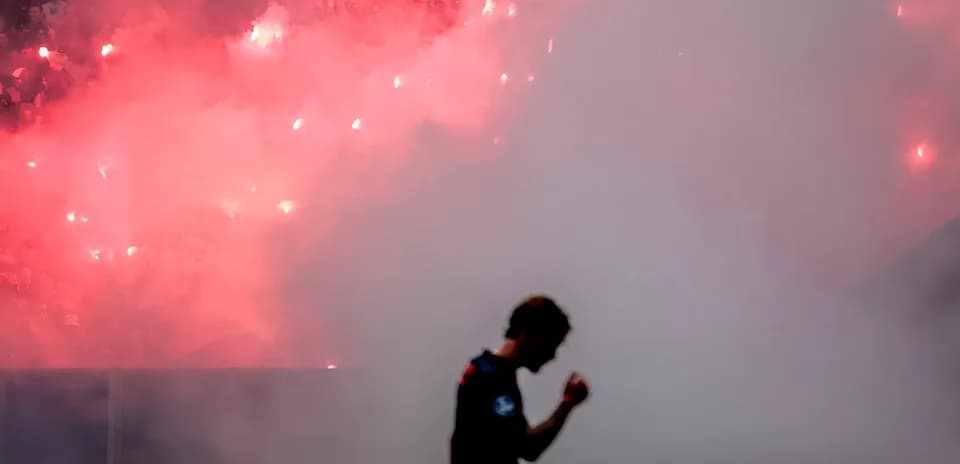 Joueur célébrant avec fumigènes en arrière-plan