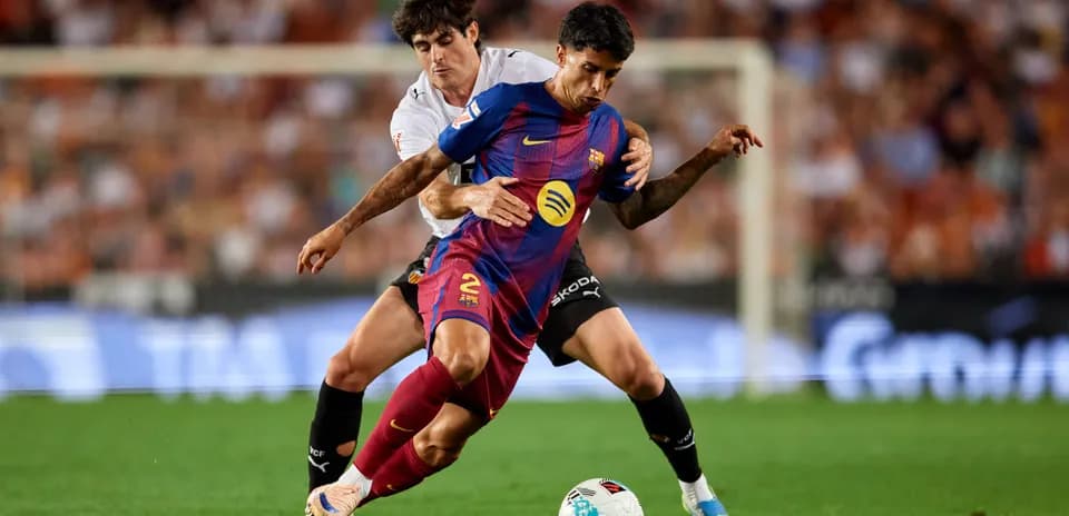 Joueur de Barcelone dribblant sous pression d'un adversaire