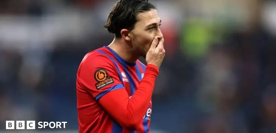 Joueur en maillot rouge et bleu touchant son visage