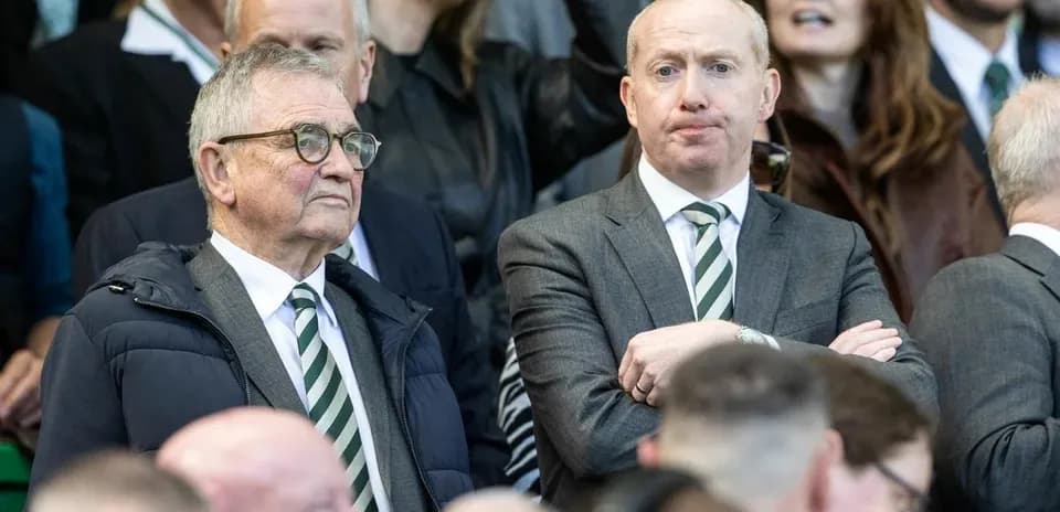 Deux hommes en costume dans les tribunes d'un match