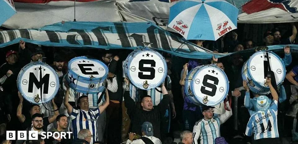 Supporters holding drums with letters at match
