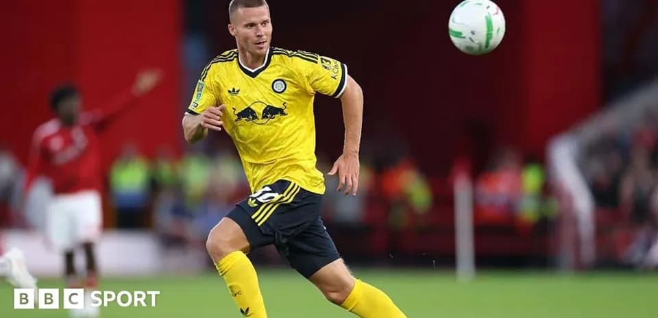 Joueur en maillot jaune courant avec le ballon