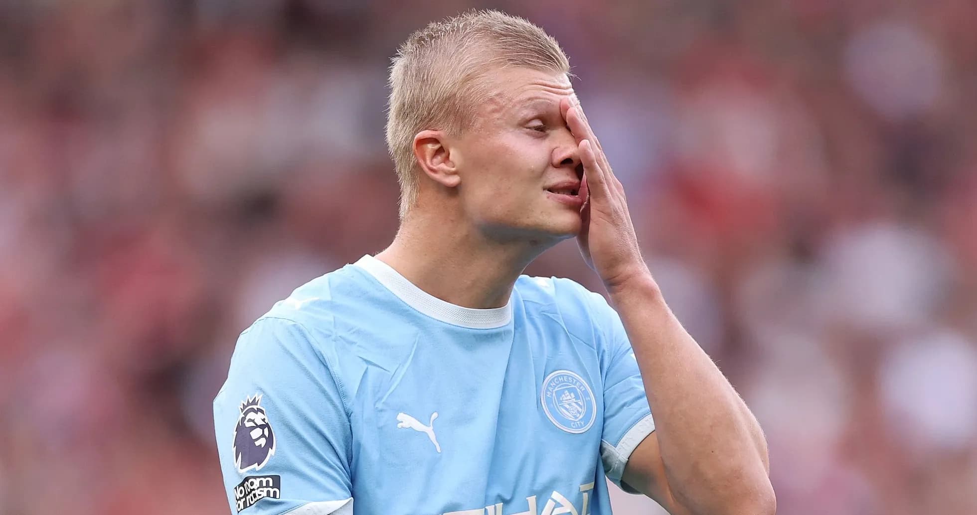 Joueur de Manchester City touchant son visage sur le terrain