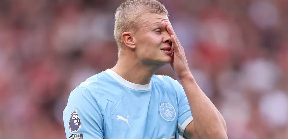 Joueur de Manchester City touchant son visage sur le terrain