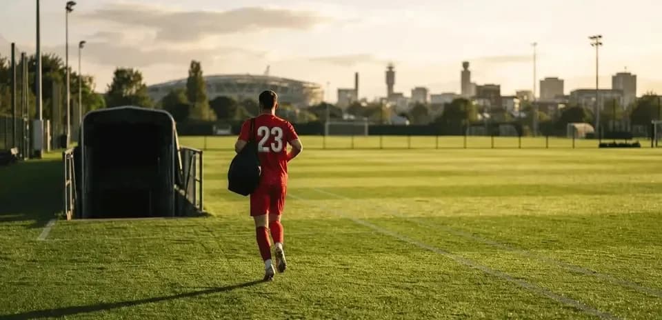 Joueur en tenue rouge entrant sur le terrain de football