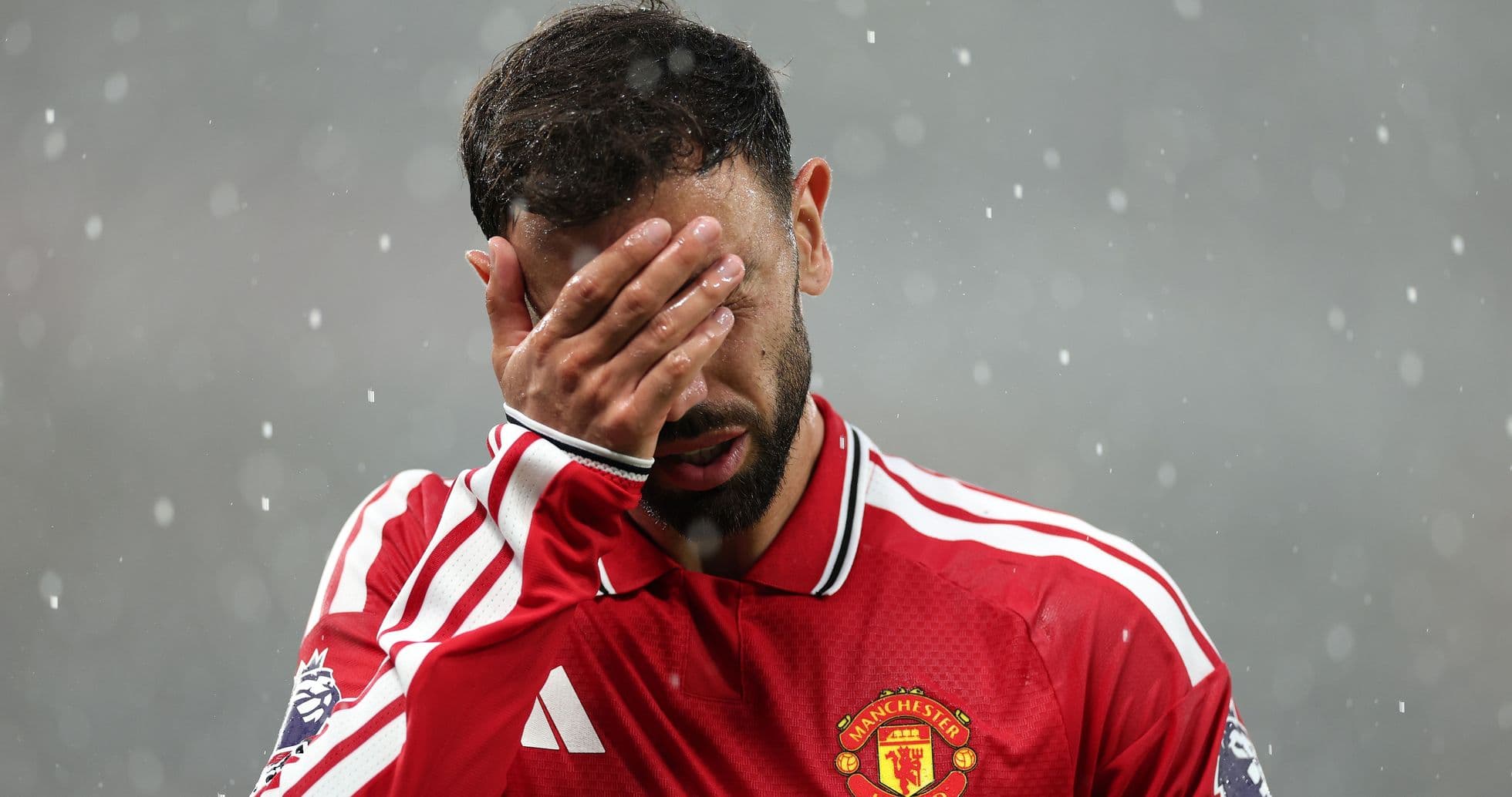 Joueur de Manchester United se couvrant le visage sous la pluie