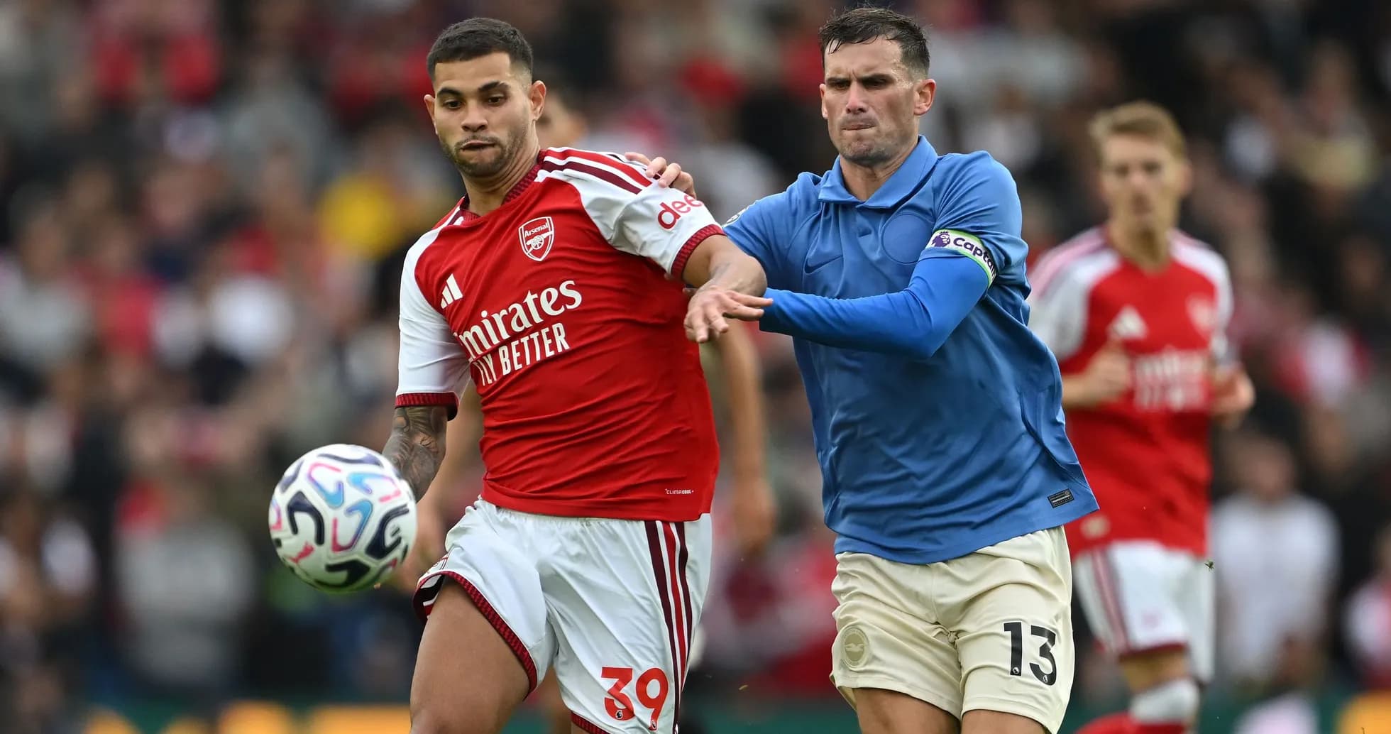 Joueur d'Arsenal dribblant sous pression d'un adversaire