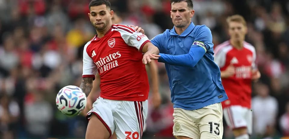 Joueur d'Arsenal dribblant sous pression d'un adversaire