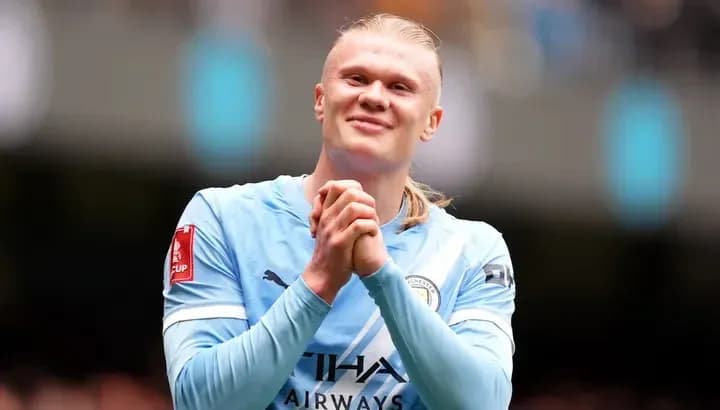 Joueur de Manchester City en maillot bleu souriant