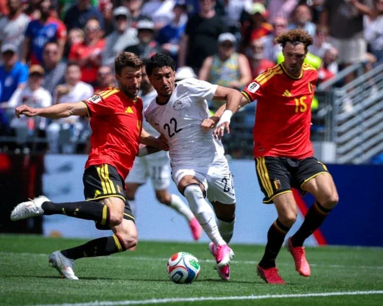 Joueur égyptien dribblant entre deux défenseurs belges