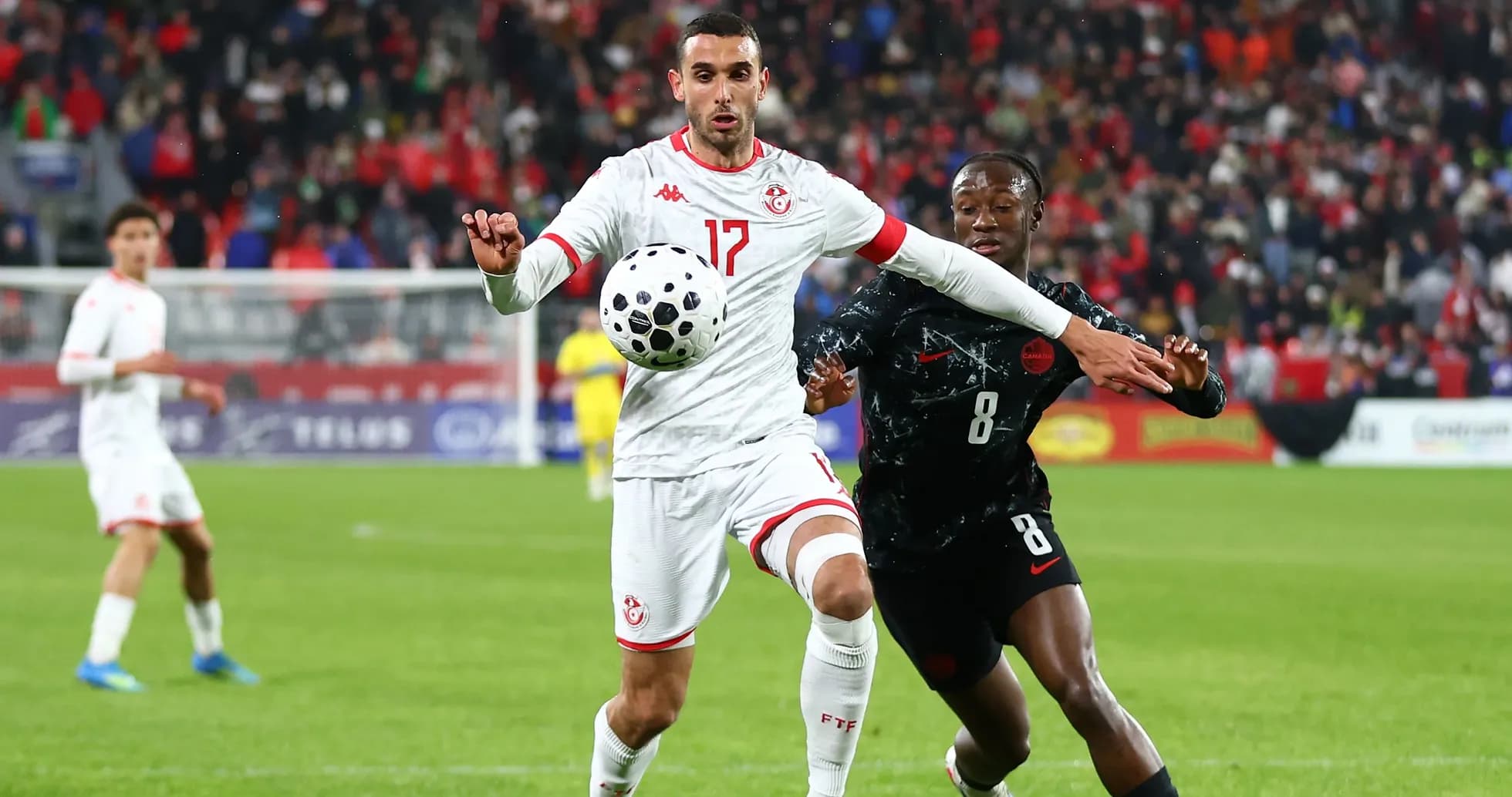 Joueur tunisien contrôlant le ballon sous pression adverse