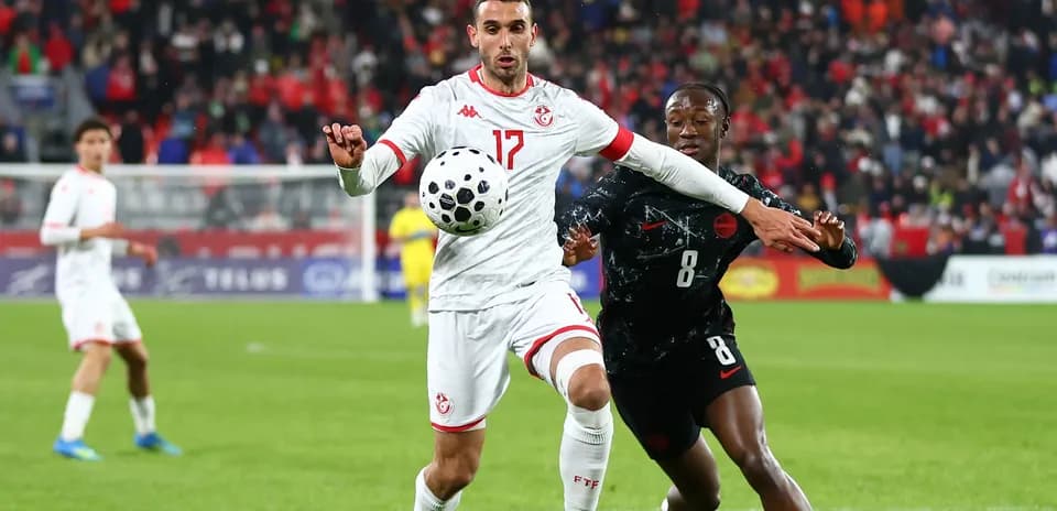 Joueur tunisien contrôlant le ballon sous pression adverse