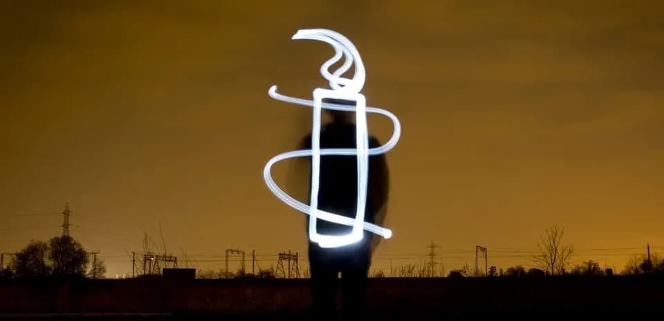 Silhouette with light drawing in nighttime landscape