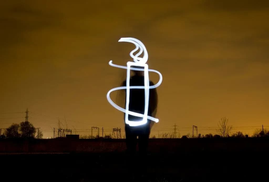 Silhouette with light drawing in nighttime landscape