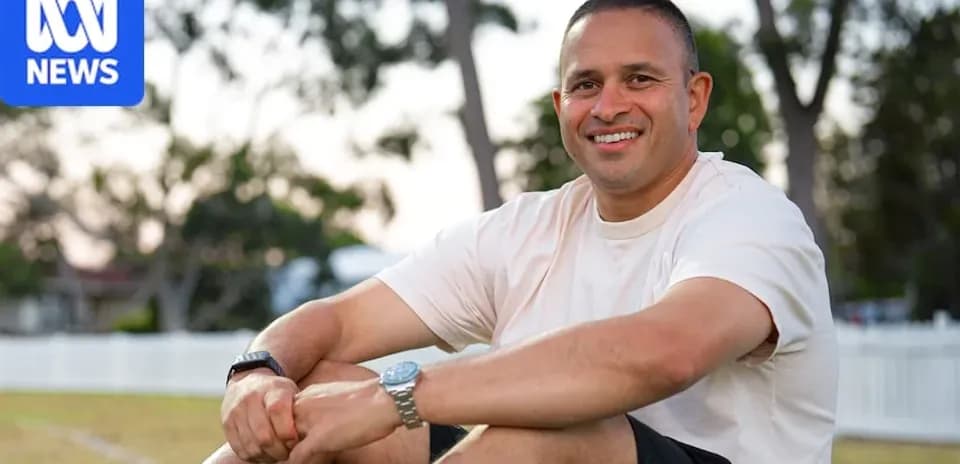 Homme souriant assis sur un terrain de sport