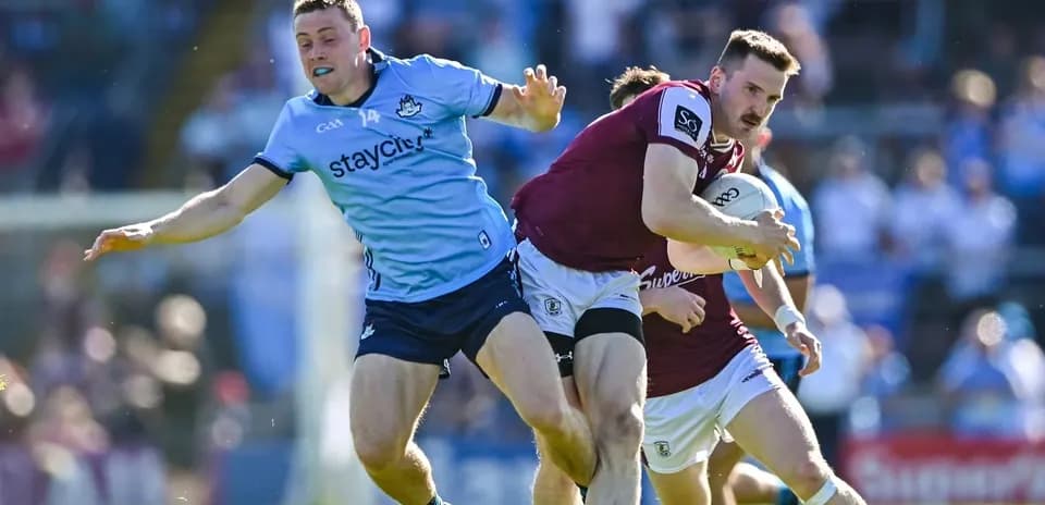 Joueur de Galways portant le ballon, attaqué par un joueur de Dublin