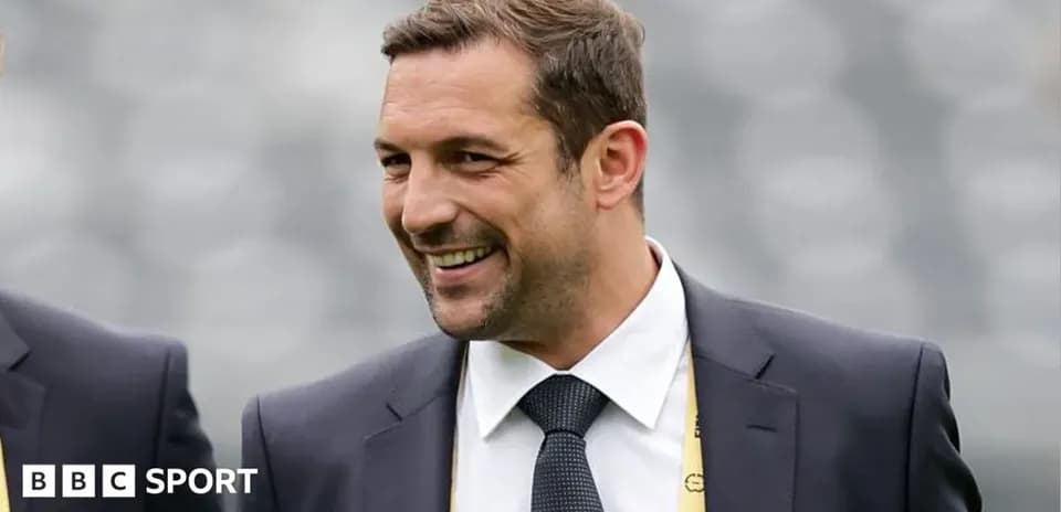 Homme souriant en costume lors d'un événement sportif