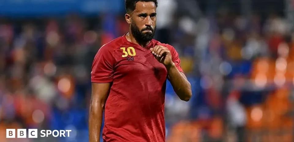 Joueur en tenue rouge marchant sur le terrain