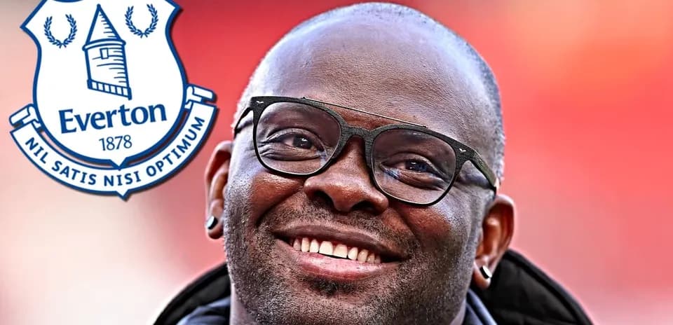 Homme souriant avec des lunettes près du logo d'Everton